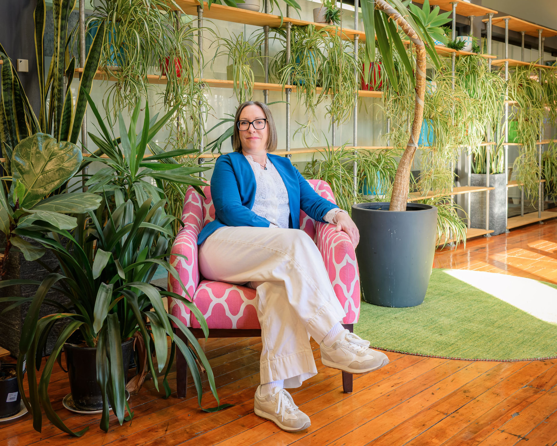 Carla seated in her plant-filled Dunedin workspace